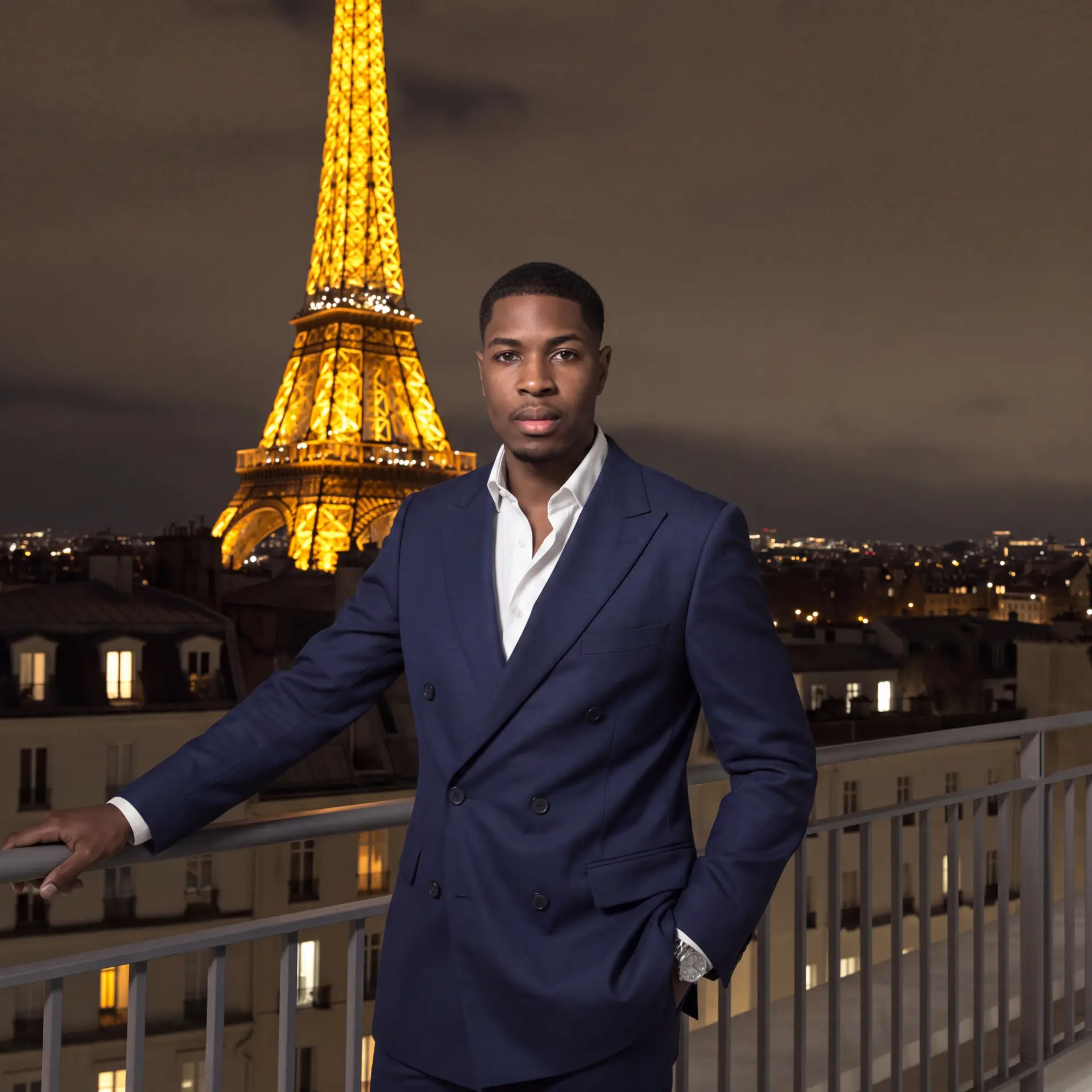 Ben on a Paris balcony with the illuminated Eiffel Tower behind him